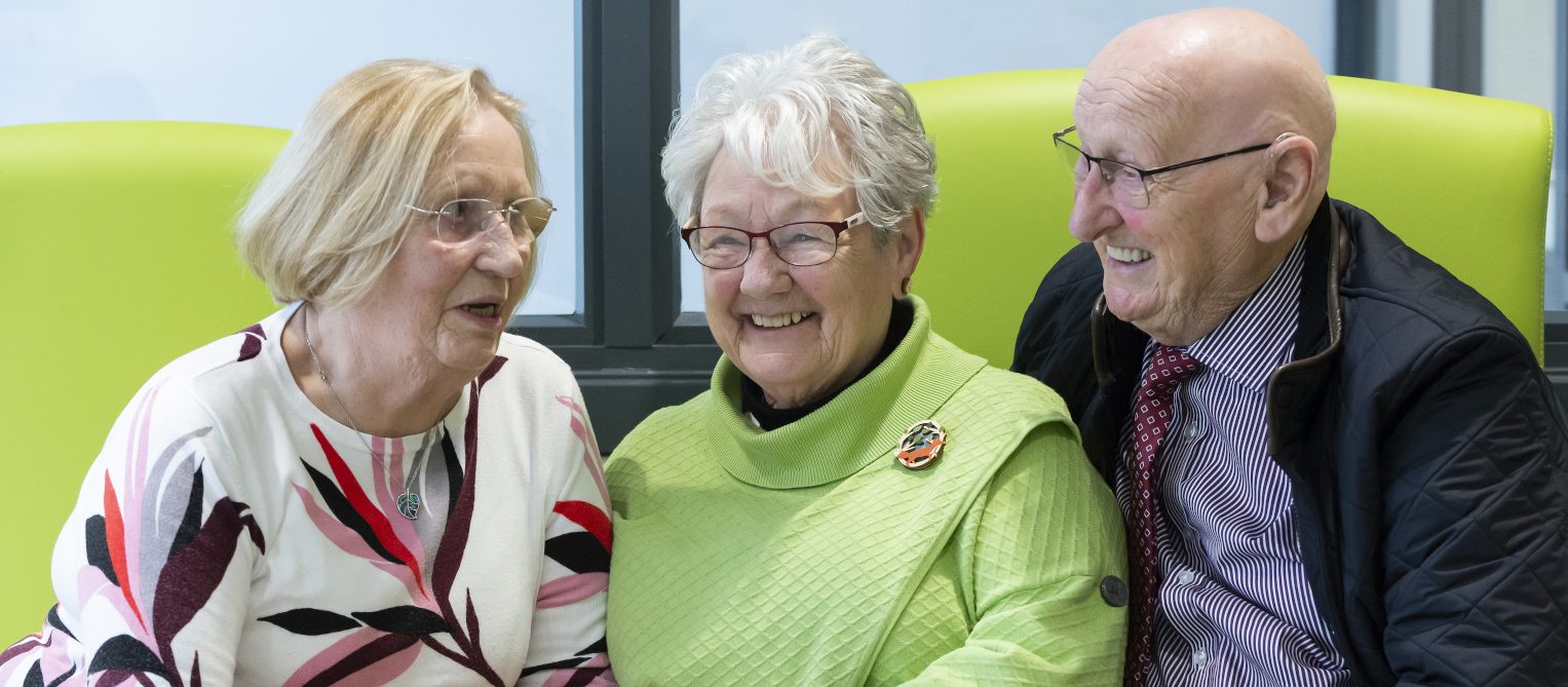 Three people holding hands and smiling